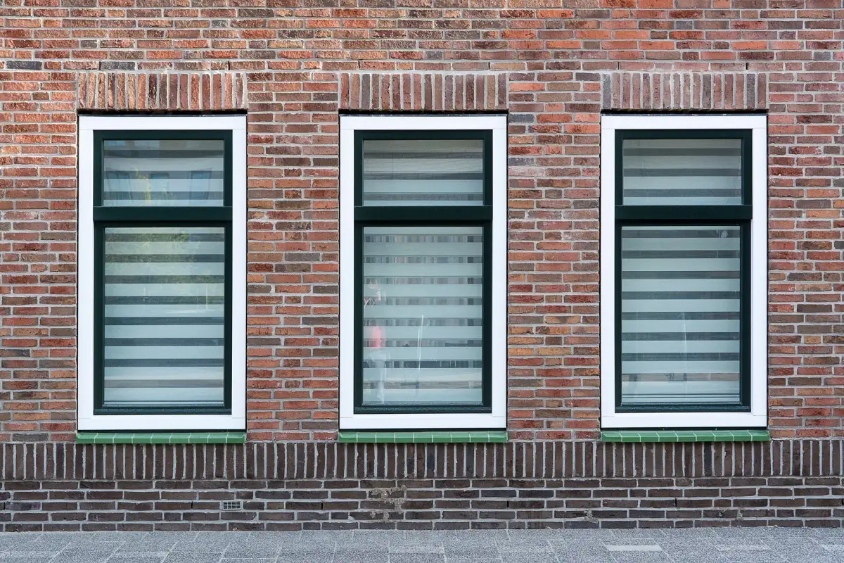 Bakstenen gevel met witte houten kozijnen
